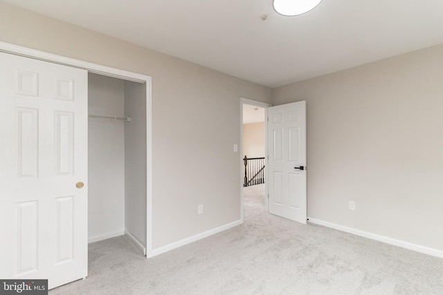 unfurnished bedroom featuring light carpet, a closet, and baseboards