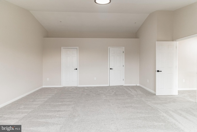 unfurnished bedroom with lofted ceiling, light carpet, and baseboards