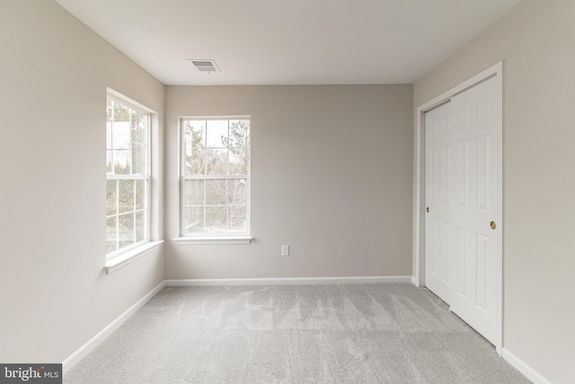 unfurnished bedroom with light colored carpet, a closet, visible vents, and baseboards