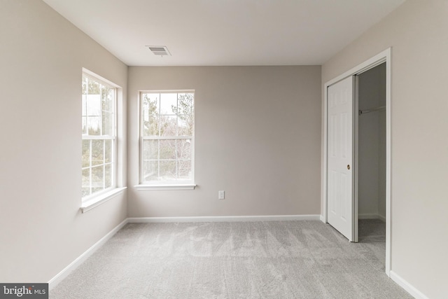 unfurnished bedroom featuring a closet, visible vents, light carpet, and baseboards