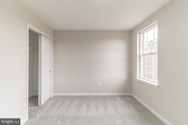 unfurnished bedroom with light carpet, multiple windows, baseboards, and a closet