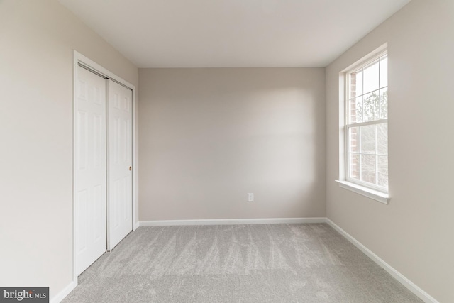 unfurnished bedroom featuring multiple windows, light carpet, and baseboards