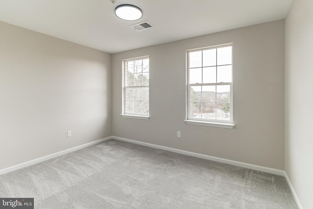 spare room with light colored carpet, visible vents, and baseboards