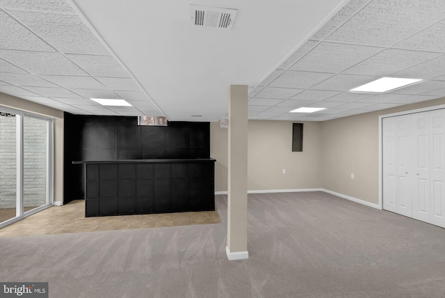 below grade area featuring light carpet, baseboards, visible vents, and a paneled ceiling