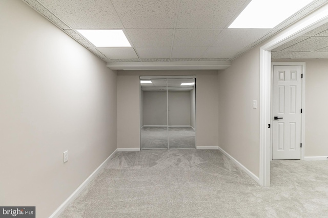 interior space with light carpet, elevator, baseboards, and a drop ceiling