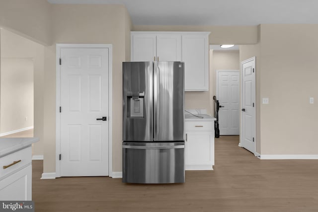 kitchen featuring light countertops, stainless steel fridge, light wood-style flooring, and white cabinets