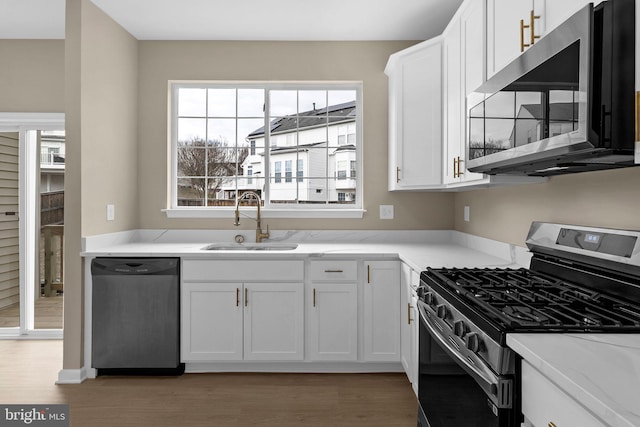 kitchen featuring white cabinetry, stainless steel appliances, a sink, and wood finished floors