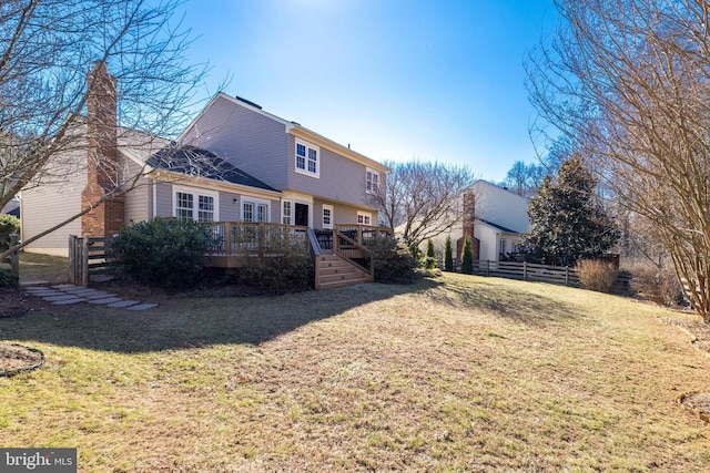 back of property with a chimney, fence, a deck, and a yard