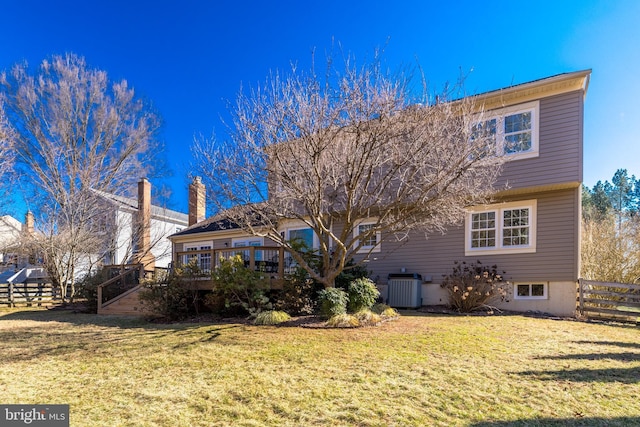 rear view of property with a yard, central AC unit, fence, and a wooden deck