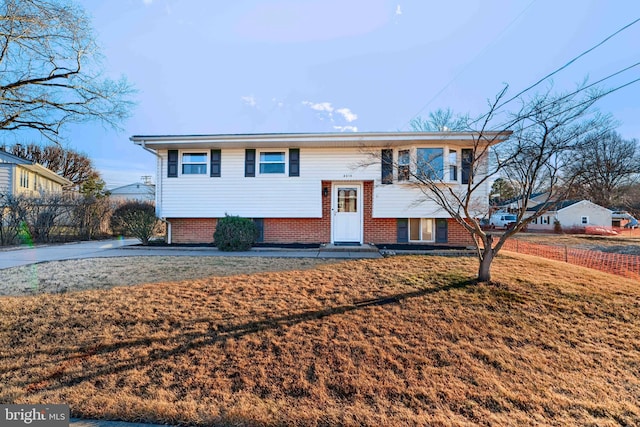 raised ranch with a front yard and brick siding