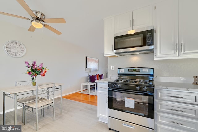 kitchen featuring light wood finished floors, stainless steel appliances, light countertops, white cabinetry, and baseboards