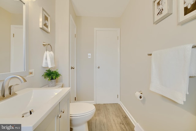 bathroom featuring toilet, wood finished floors, and vanity