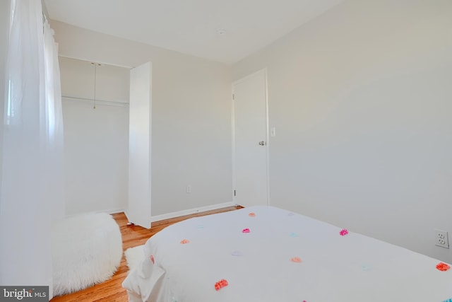 bedroom with light wood-style floors, baseboards, and a closet