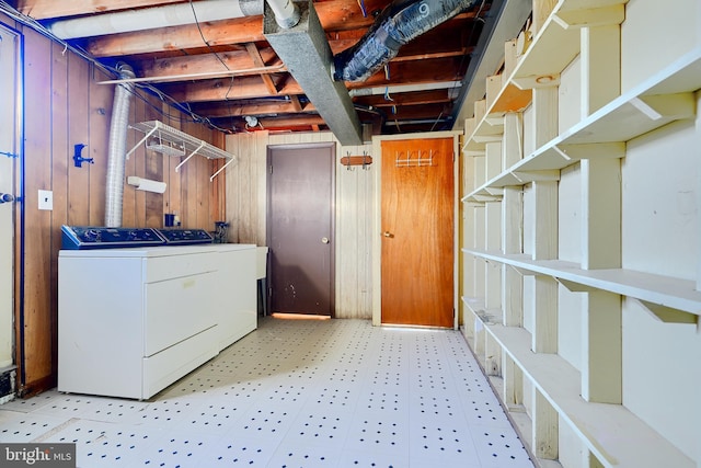 washroom featuring laundry area, light floors, washing machine and clothes dryer, and wooden walls