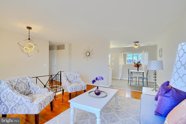 living room with baseboards, visible vents, and wood finished floors