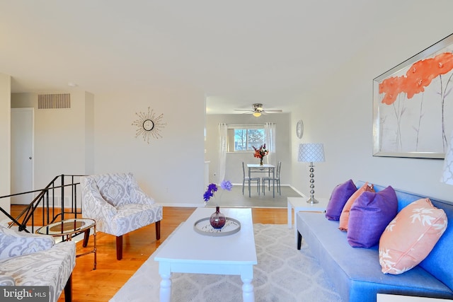 living area with baseboards, visible vents, and wood finished floors