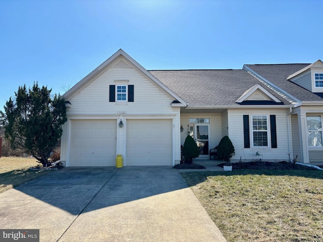 view of front of house featuring a shingled roof, a front yard, and concrete driveway