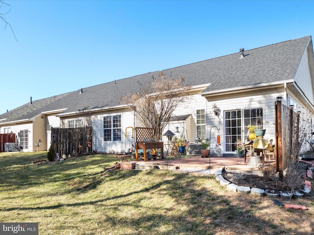 back of house with a yard, a patio, and roof with shingles