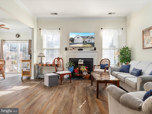 living area with visible vents, crown molding, a fireplace, and wood finished floors