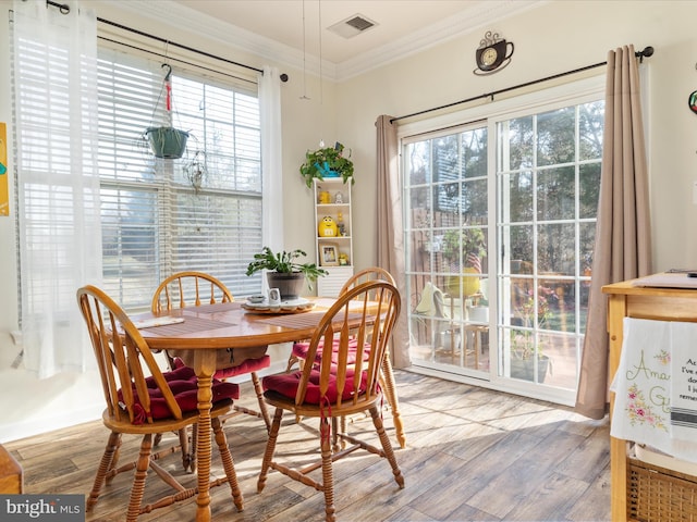 dining space featuring visible vents, ornamental molding, and wood finished floors