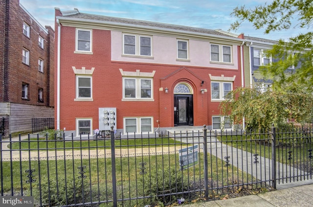 view of front of home featuring a fenced front yard, a front yard, and brick siding