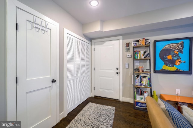 foyer with dark wood-style flooring and baseboards