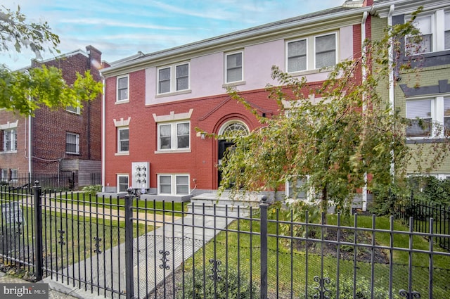 view of property with a fenced front yard, a front lawn, and brick siding