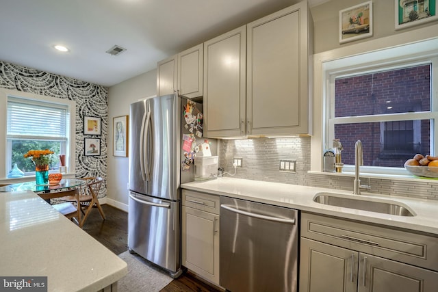 kitchen with decorative backsplash, dark wood-style floors, appliances with stainless steel finishes, light countertops, and a sink