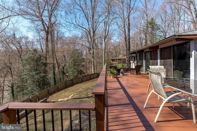 wooden deck featuring a yard, a fenced backyard, and a sunroom