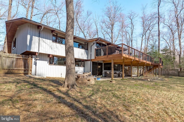 rear view of property featuring a deck, stairway, a yard, and fence