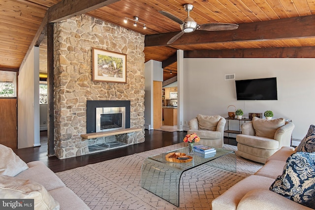 living room with lofted ceiling with beams, visible vents, a stone fireplace, and wood finished floors