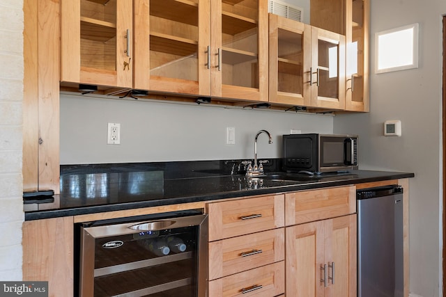 kitchen featuring beverage cooler, dark countertops, and light brown cabinetry