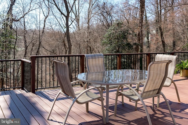 wooden terrace with a wooded view and outdoor dining area