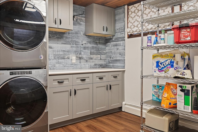 washroom with wood finished floors, stacked washer / dryer, and cabinet space