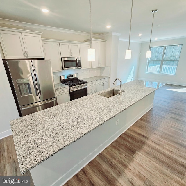 kitchen with tasteful backsplash, appliances with stainless steel finishes, white cabinets, a sink, and light wood-type flooring