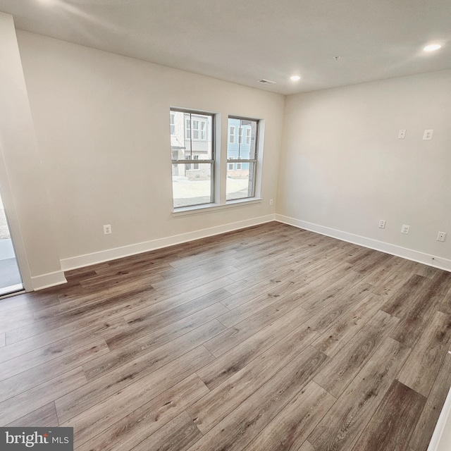 empty room with baseboards, wood finished floors, and recessed lighting