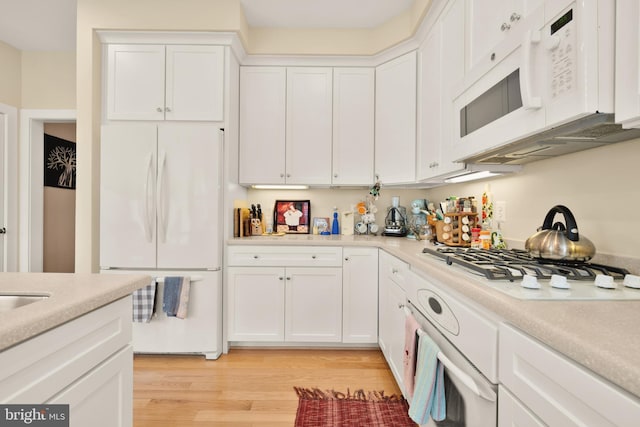 kitchen featuring white appliances, white cabinetry, light countertops, and light wood-style floors