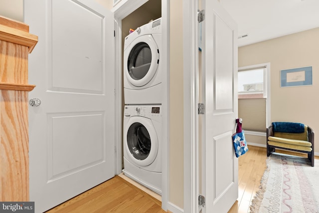 washroom featuring stacked washing maching and dryer, laundry area, and light wood finished floors