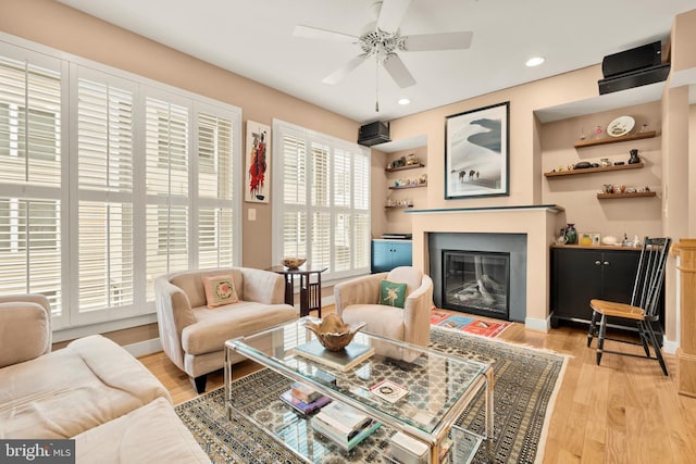 living room with a glass covered fireplace, baseboards, and light wood finished floors