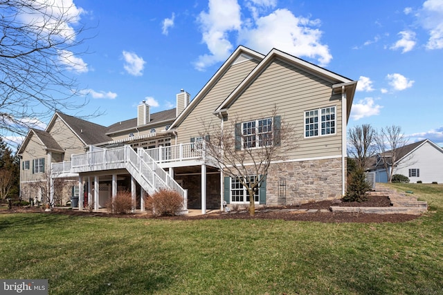 rear view of house featuring stairway, a chimney, stone siding, a deck, and a lawn