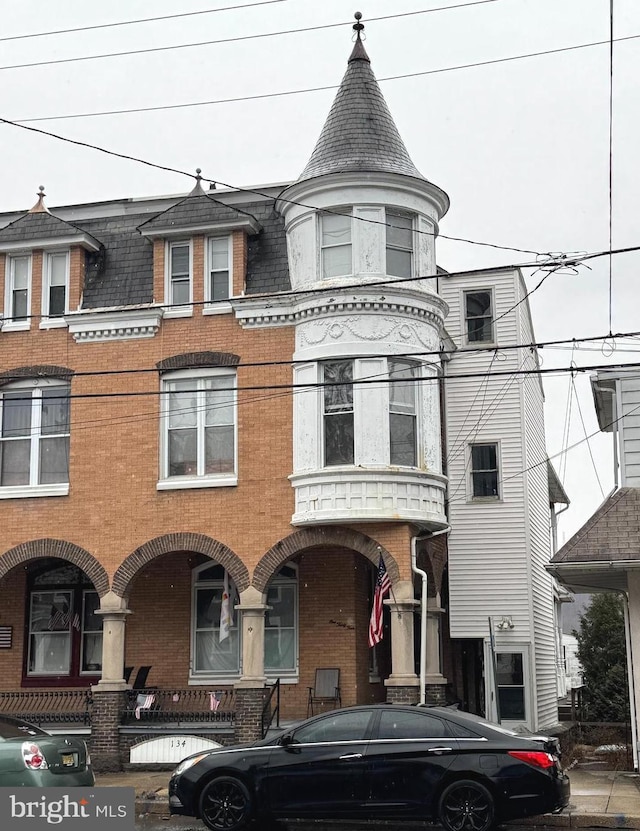 view of front of house featuring brick siding and mansard roof