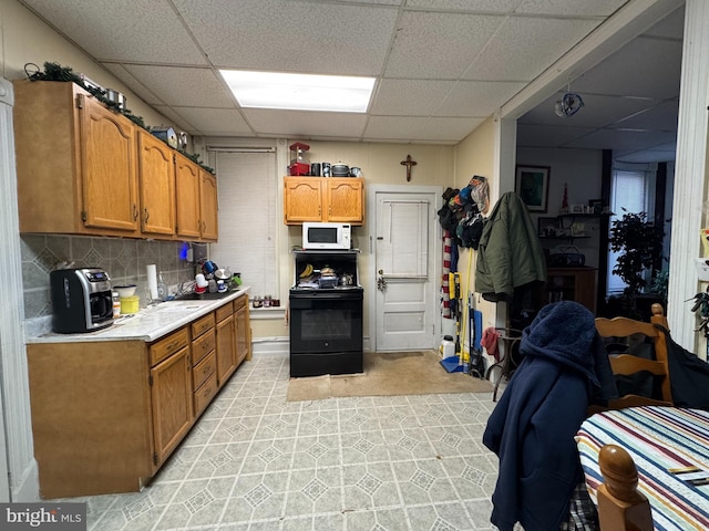 kitchen featuring brown cabinetry, light countertops, black / electric stove, and white microwave