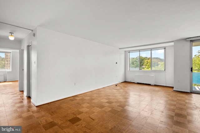 empty room featuring baseboards, radiator heating unit, and a healthy amount of sunlight