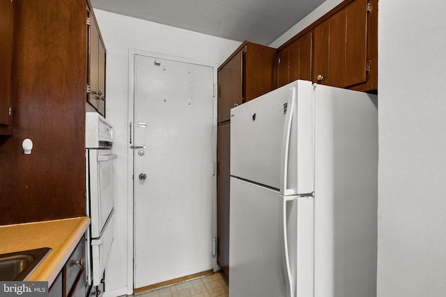 kitchen featuring light floors, white appliances, and light countertops