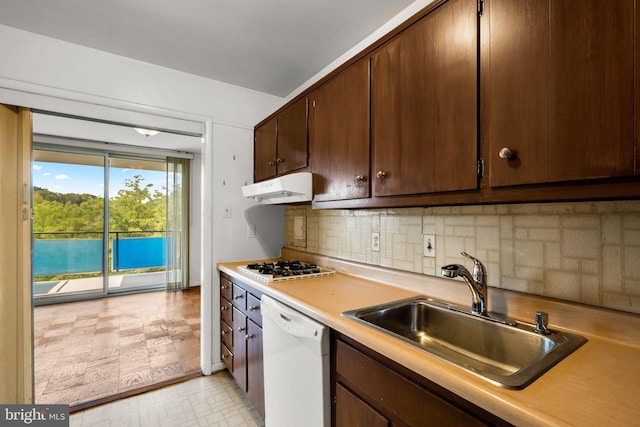 kitchen with white appliances, a sink, light countertops, under cabinet range hood, and backsplash