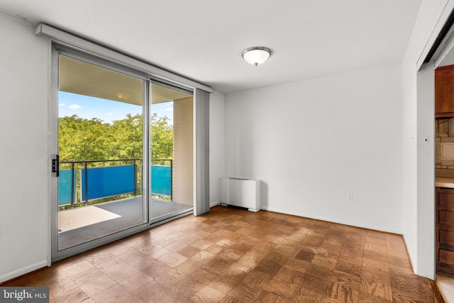 empty room featuring radiator heating unit, a wall of windows, and baseboards