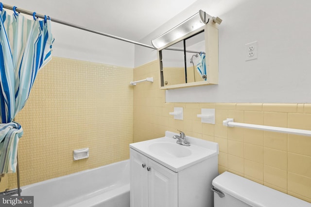 bathroom featuring a wainscoted wall, tile walls, toilet, shower / bath combo, and vanity