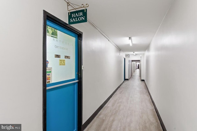 corridor featuring light wood-style flooring and baseboards