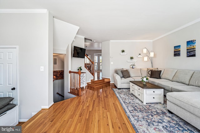 living room featuring visible vents, baseboards, stairs, light wood-style floors, and crown molding