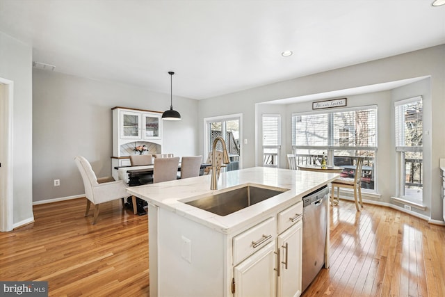 kitchen featuring visible vents, a sink, white cabinets, light wood-style floors, and stainless steel dishwasher